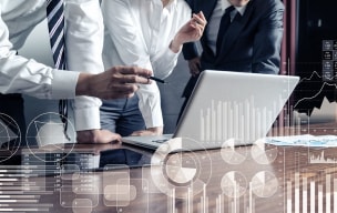 Business team reviewing data on a laptop with digital charts overlay