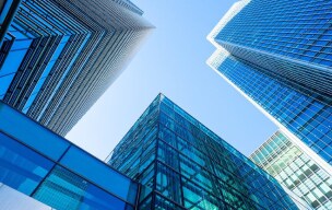 Businessman in a suit holding a smartphone while standing near a window in a modern office