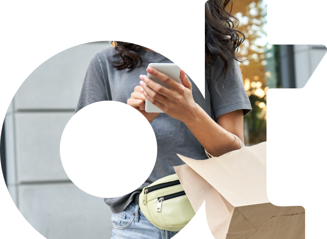 A person texting on mobile phone and holding a shopping bag