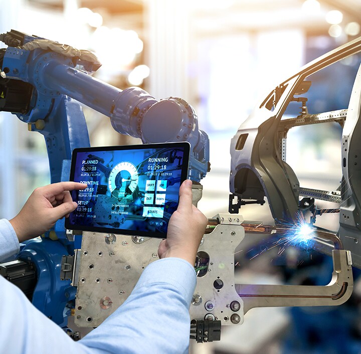 A person holding tablet infront of automotive machines