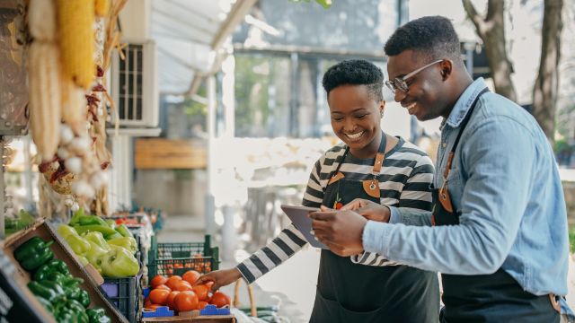 Two grocery employees smiling and looking at tablet