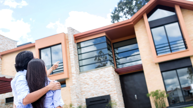 couple looking at a modern two-story home exterior on a bright sunny day