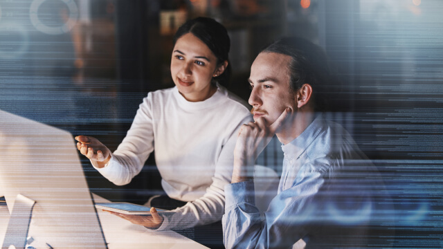 Two people discussing work on office computer