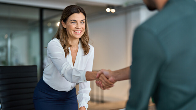 Two people shaking hands during meeting in office